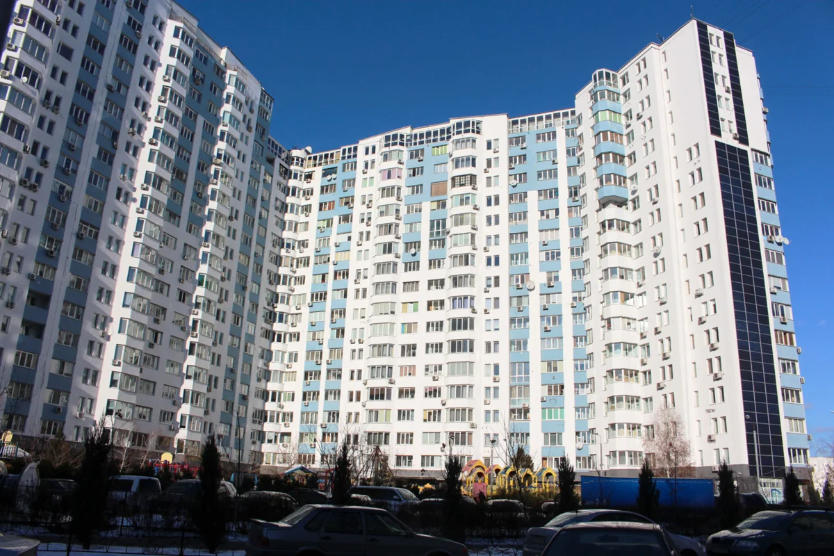 Сучасні багатоповерхівки з біло-блакитними фасадами та парковкою взимку