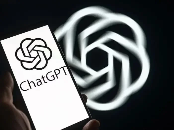Смартфон с логотипом ChatGPT на экране на фоне большого размытого логотипа, иллюстрация масштабного сбоя сервиса