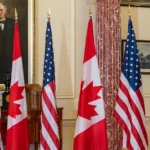 Прапори США та Канади в офіційній залі на тлі портрета, ілюструючи запровадження 50% мит США на імпорт з Канади Дональдом Трампом