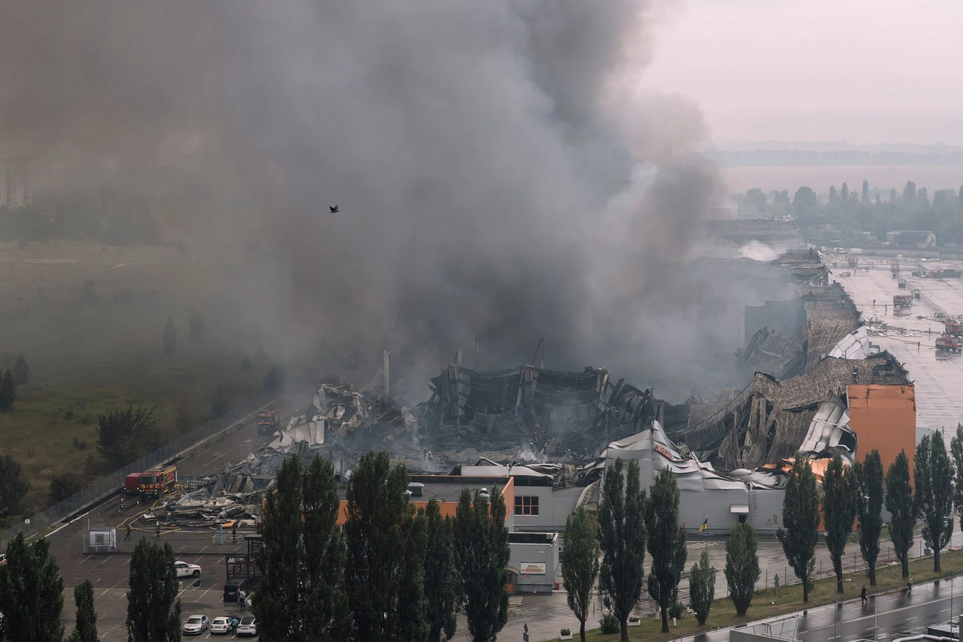 Зруйнований склад після обстрілу Києва з густим димом і пожежними машинами