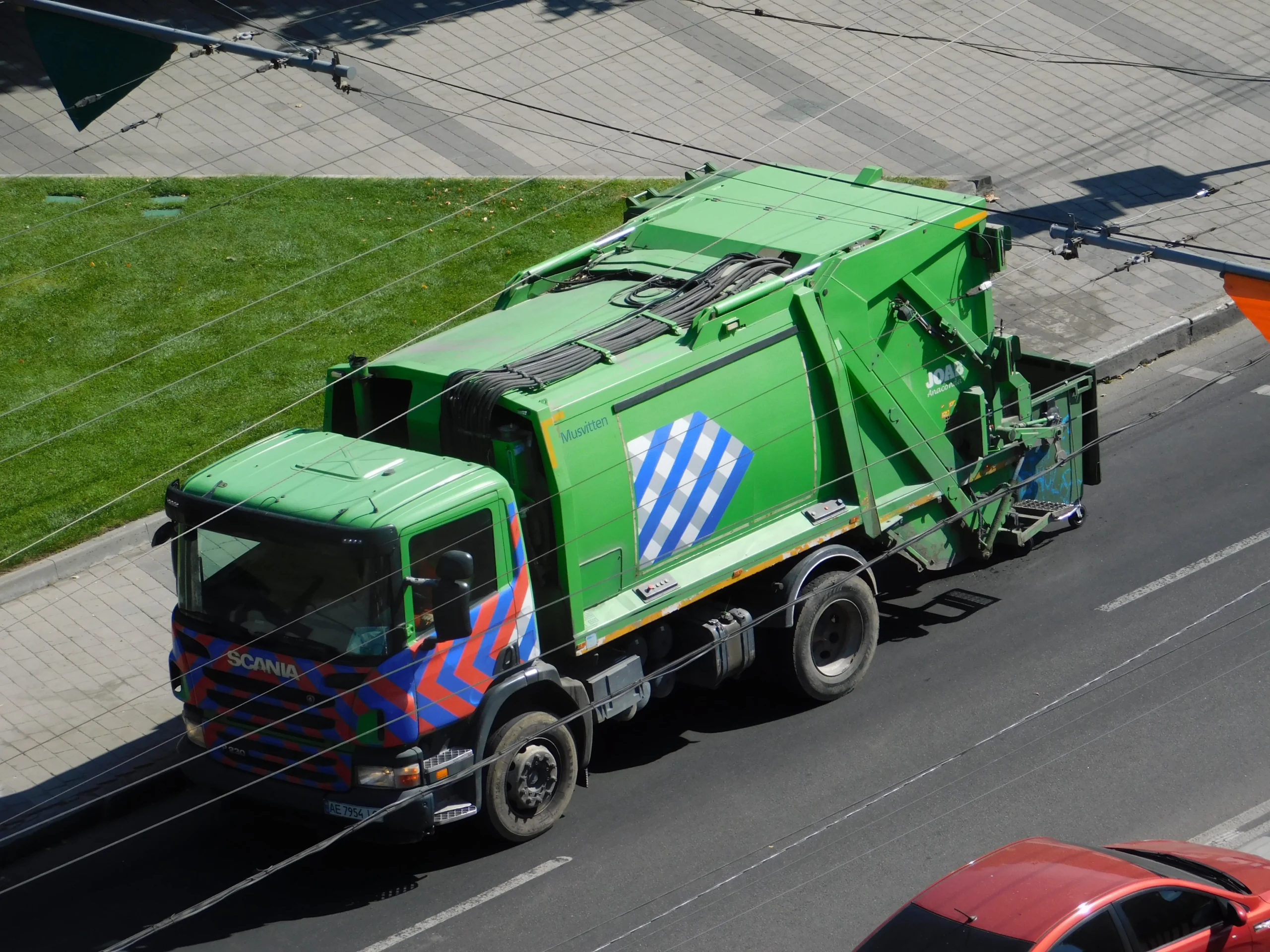 Зелений сміттєвоз Scania з кузовом JOAB їде вулицею Києва