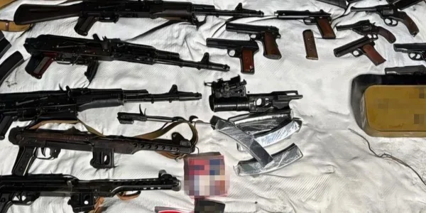 Автомати пістолети магазини та зброя розкладені на білій тканині